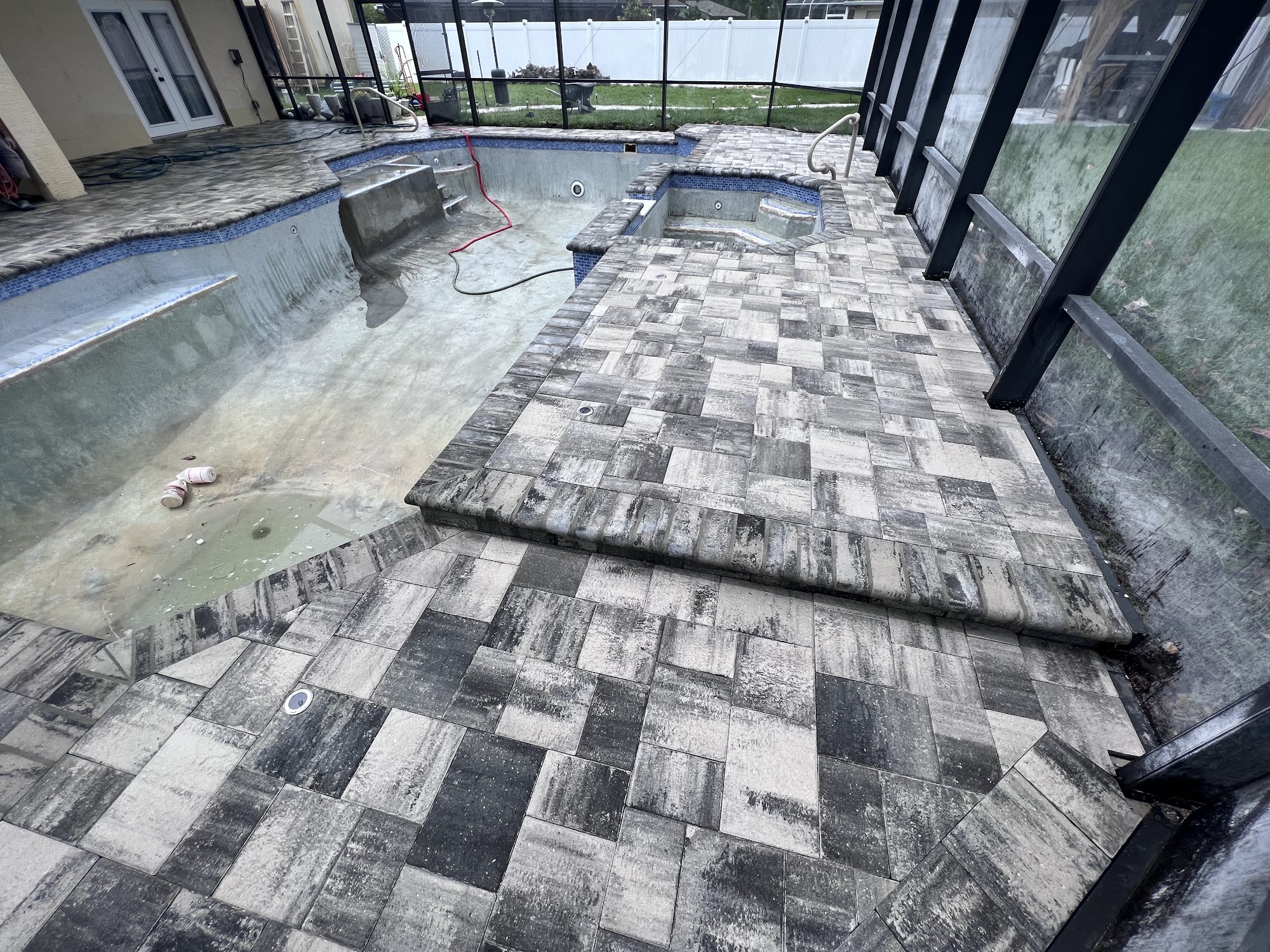 Travertine paver pool deck and screen-enclosed lanai mid-build
